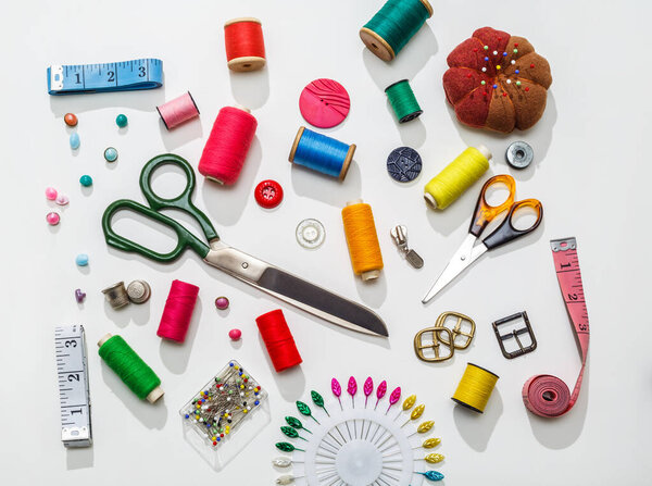 Needlework accessories. A set of sewing accessories for fabric and spools of thread, scissors and a thimble on a white background. View from abov