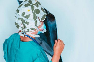 Cerrah gibi giyinmiş, röntgen çektirirken doktorculuk oynayan sevimli çocuk.