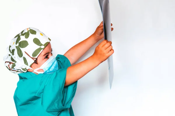 cute kid playing doctor dressed as a surgeon examining an x-ray