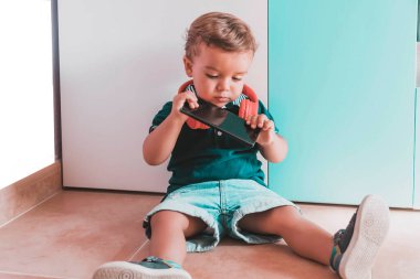 çocuk cep telefonu ve kulaklığı olan videolar dinliyor