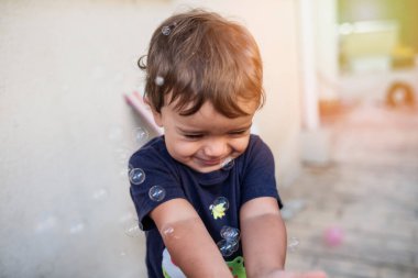 Mavi tişörtlü çocuk sabun köpüğüyle oynuyor