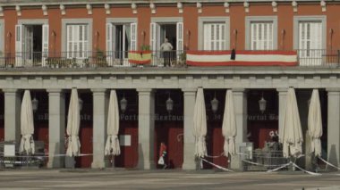 Madrid Plaza Belediye Başkanı 'nın bir sakini, Coronavirus tecridi sırasında meydanın verandasından geçen bir adam balkonunda güneşin tadını çıkarıyor.