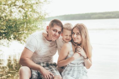 Anne, baba ve oğul kıyıya yakın bir yerde oturuyorlar.