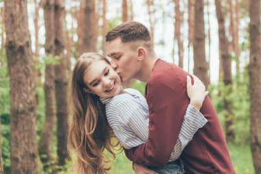 Adam ormanda bir kızı öpüyor.