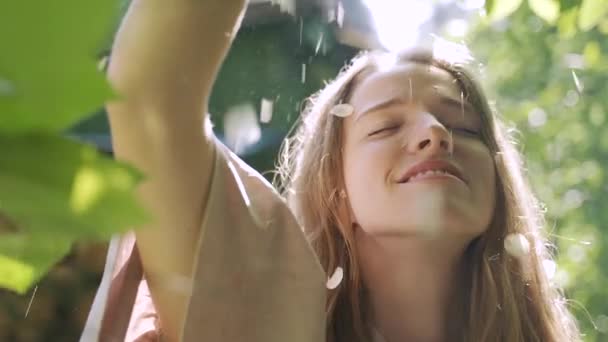 Florile de iasomie cad pe fața unei fete tinere. raze de soare și strălucire, mișcare lentă — Videoclip de stoc