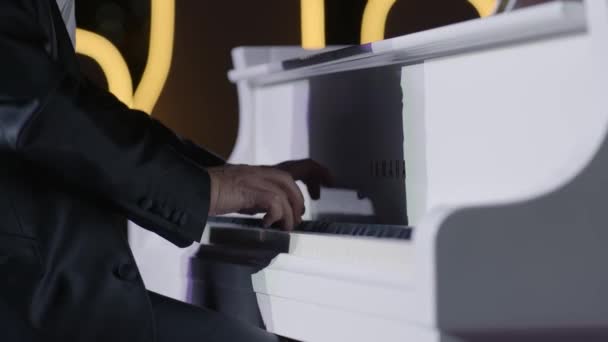 ドバイ アラブ首長国連邦 2020年3月7日 黒いジャケットを着たバーチャル ピアニストが白いピアノを演奏します 明るい光は厳しい影を作り出します — ストック動画