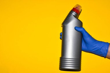 Eldivenli bir el bir şişe temizlik dezenfektanı tutar. Metin için yer.