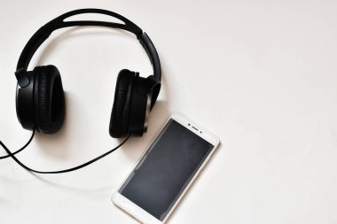 Siyah kulaklıklar ve cep telefonu beyaz arka planda izole edilmiş. metin için yer