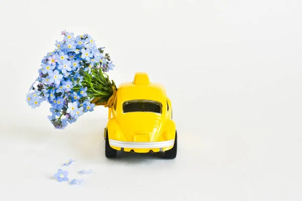 Toy car broadcasts a bouquet of flowers on a white background. place for text. concept of March 8, Valentine\'s Day, holiday