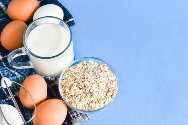 Mavi arka planda süt, yumurta ve yulaf ezmesi. Sağlıklı beslenme, beslenme.