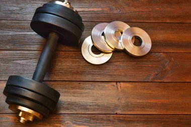 Ahşap arka planda profesyonel dambıl ve diskler. Üst görünüm, metin için yer.