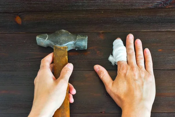 Mano Con Dedo Lesionado Sostiene Martillo Sobre Fondo Madera Oscura —  Fotos de Stock