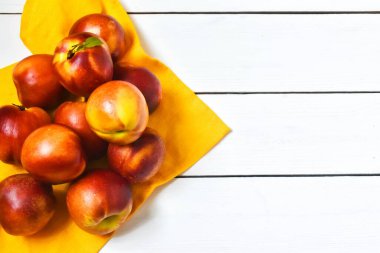 Beyaz ahşap arka planda keten bir masa örtüsü üzerinde olgun şeftaliler. Düz yatış, üst manzara. Yaz meyveleri konsepti.