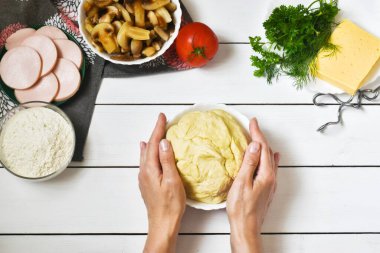 Kadın elleri beyaz bir tahta üzerinde pizza hamuru pişiriyor. düz yatak, pizza tarifi konsepti.