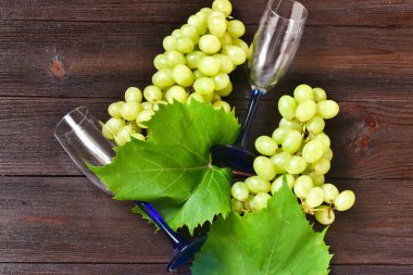 Ahşap arka planda bir demet yeşil üzüm ve şarap kadehi. Üst görünüm, düz görünüm, kopyalama alanı.