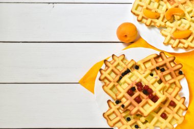 Beyaz ahşap arka planda taze kayısılı Belçika waffleları. Üst görünüm, düz görünüm, kopyalama alanı.