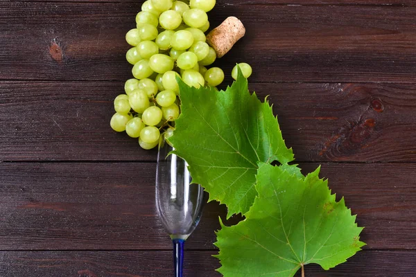 A bunches of green grapes and wine glasses on  wooden background. Top view, flat lay, copy space.