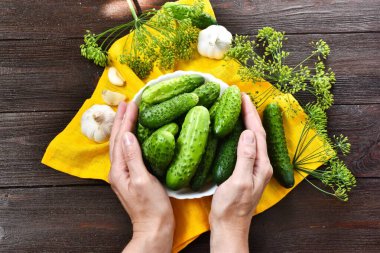 Ahşap bir arka planda salatalık servis eden eller. Üst görünüm, yakın çekim.