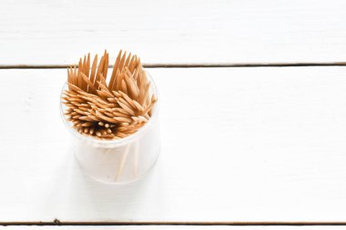 Beyaz ahşap arka planda kürdanlı bir şişe. Üst görünüm, kopyalama alanı, düz uzanma.