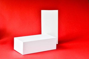 Kırmızı arka planda duran beyaz kutular. Boş, markasız bir dükkan. Kozmetik ürünler için vitrin. Ürün reklamı. Model tasarımı. Kozmetik ve güzellik kavramı.