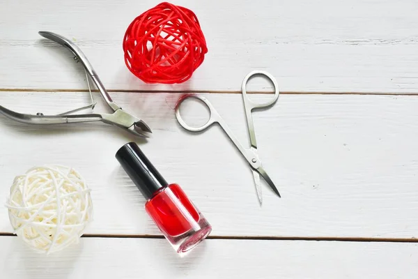 Manicure set and nail polish on a white wooden background.