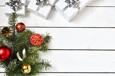 Beyaz hediye kutularıyla beyaz ahşap arka planda Noel kompozisyonu, köknar dallı gümüş bir kurdele, oyuncaklar. Tebrik etmek için yer ayır. Yeni yıl, Noel konsepti..