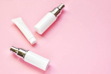 Pembe arka planda beyaz plastik şişelerde cilt bakım ürünleri. Boş konteynırlar. Kozmetik güzellik ürünleri. Reklam kavramı. Kopya alanı, düz yatış..