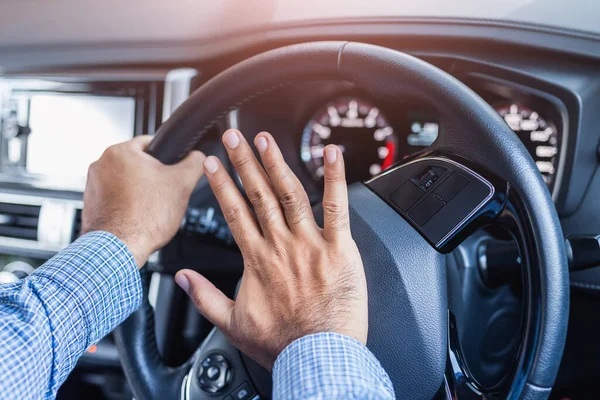 Hand man pushing car horn while driving car.