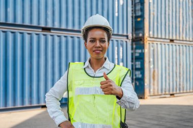 Kara ustabaşı kadın işçi konteyner kargo limanında konteynırları yüklemeye çalışıyor. Afrika rıhtımı kadın personel lojistik ithalat ihracat konsepti.