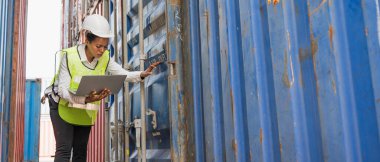 Kara ustabaşı kadın işçi konteynır kargo limanında kontrol ediyor dizüstü bilgisayarla konteynırları yüklüyor. Afrika rıhtımı kadın personel lojistik ithalat ihracat konsepti.