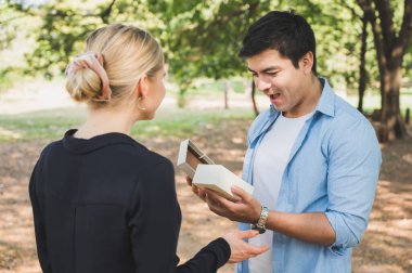 Genç aşıklar parkta hediye paketi veriyorlar. Romantik bir şekilde..