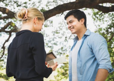 Genç aşıklar parkta hediye paketi veriyorlar. Romantik bir şekilde..