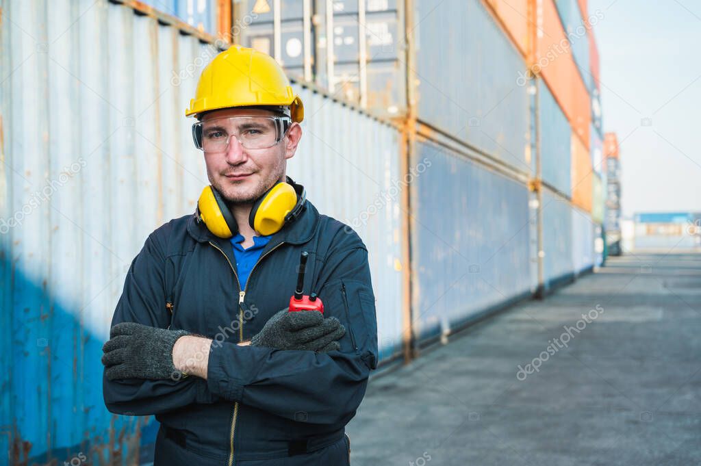 Foreman worker working checking at Container cargo harbor holding radio walkie-talkie to loading containers. Dock male staff business Logistics import export shipping concept.