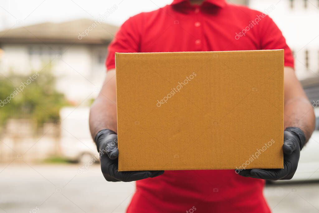 Postman in red wearing glove uniform holding package.