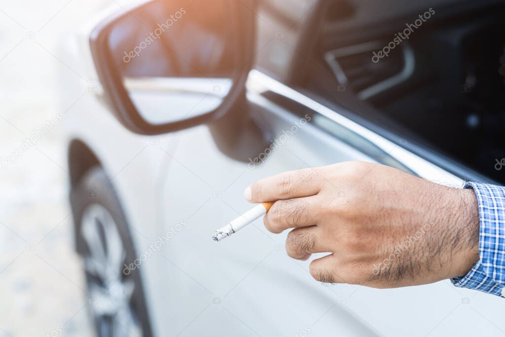 Young man smoking a cigarette in car.