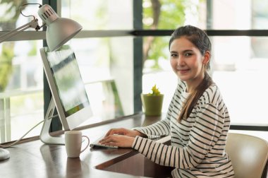 Güzel Asyalı kadın sabahları evden çalışıyor. Bilgisayarla çalışan Asyalı genç bir kadın evde kalıyor..