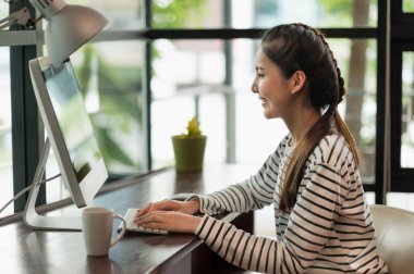 Güzel Asyalı kadın sabahları evden çalışıyor. Bilgisayarla çalışan Asyalı genç bir kadın evde kalıyor..