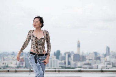 Asyalı seksi kadın binanın çatısında dans ediyor..