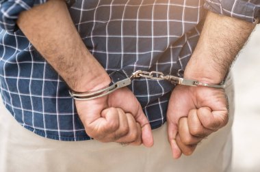 Elleri kelepçeli bir mahkum hapiste. Kelepçeli Elleri Kapat.