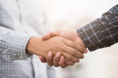 Başarı anlaşması işine el sıkışan iki adam. Şehir manzarası arka planında Scott tişörtü giyen iş adamları.