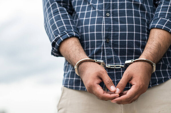 Prisoner man in jail with handcuffs. Close up Shackled in Hands.