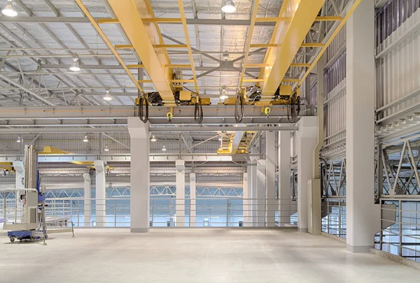 Overhead crane and concrete floor inside factory building for background.