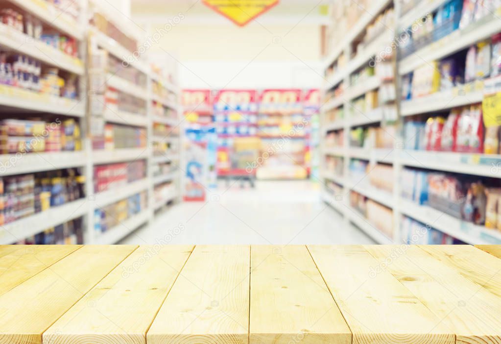 Blurred photo of aisle and products on shelf montage with wood table for shopping background.