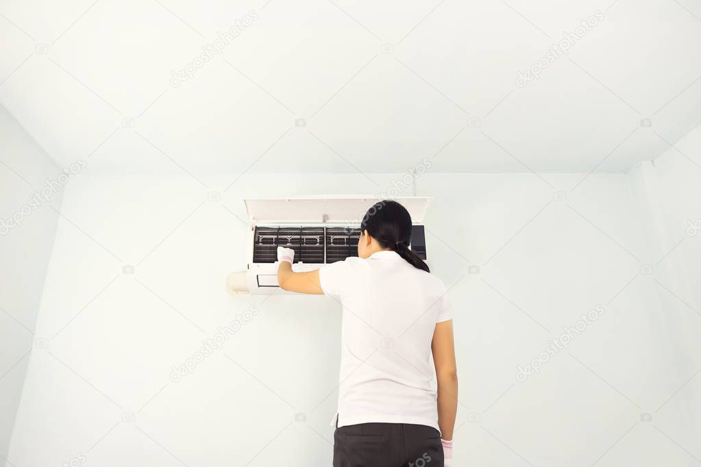 Woman cleaning air conditioner inside room