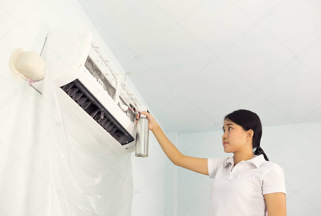 Woman cleaning air conditioner by foaming agent.
