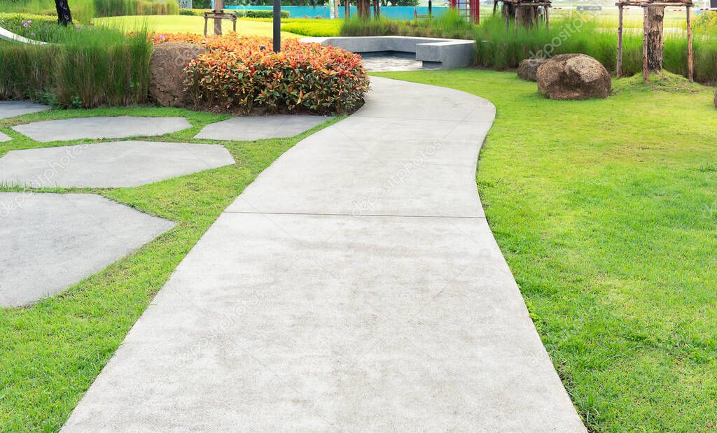 Walkway and bush in garden. Also called concrete pavement, floor, passage, path, footpath, pathway or passageway. Include natural plant, lawn and grass. For walking along and decorative park, garden.