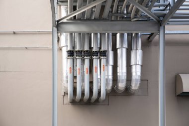 Industrial pipework installed on exterior of modern building. Utility infrastructure to combines architecture and engineering. Represents construction, mechanical system and building services design.