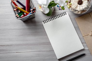 Tahta beyaz bir masanın üzerinde kalemle bir defter.