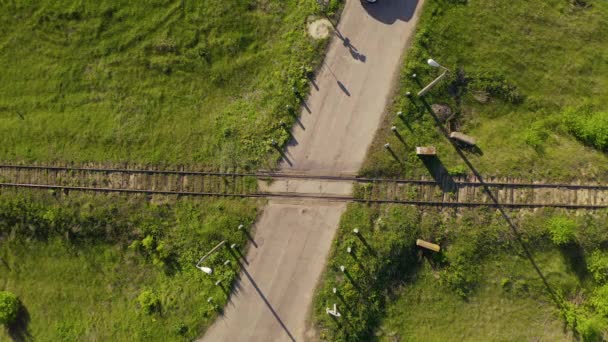 Veículo que passa pela estrada de ferro que cruza na paisagem rural. Visão aérea de cima para baixo . — Vídeo de Stock