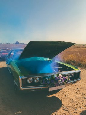 Bozuk düğün retro arabası, açık kaput ve mavi duman motordan geliyor.